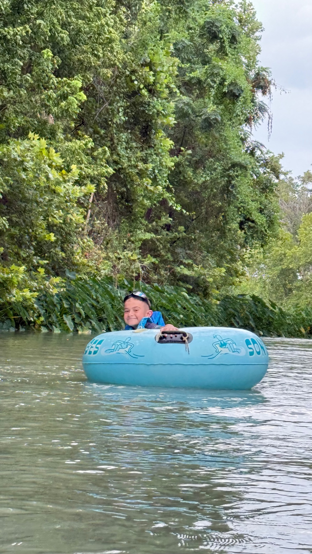 Smiling kid tubing on the river