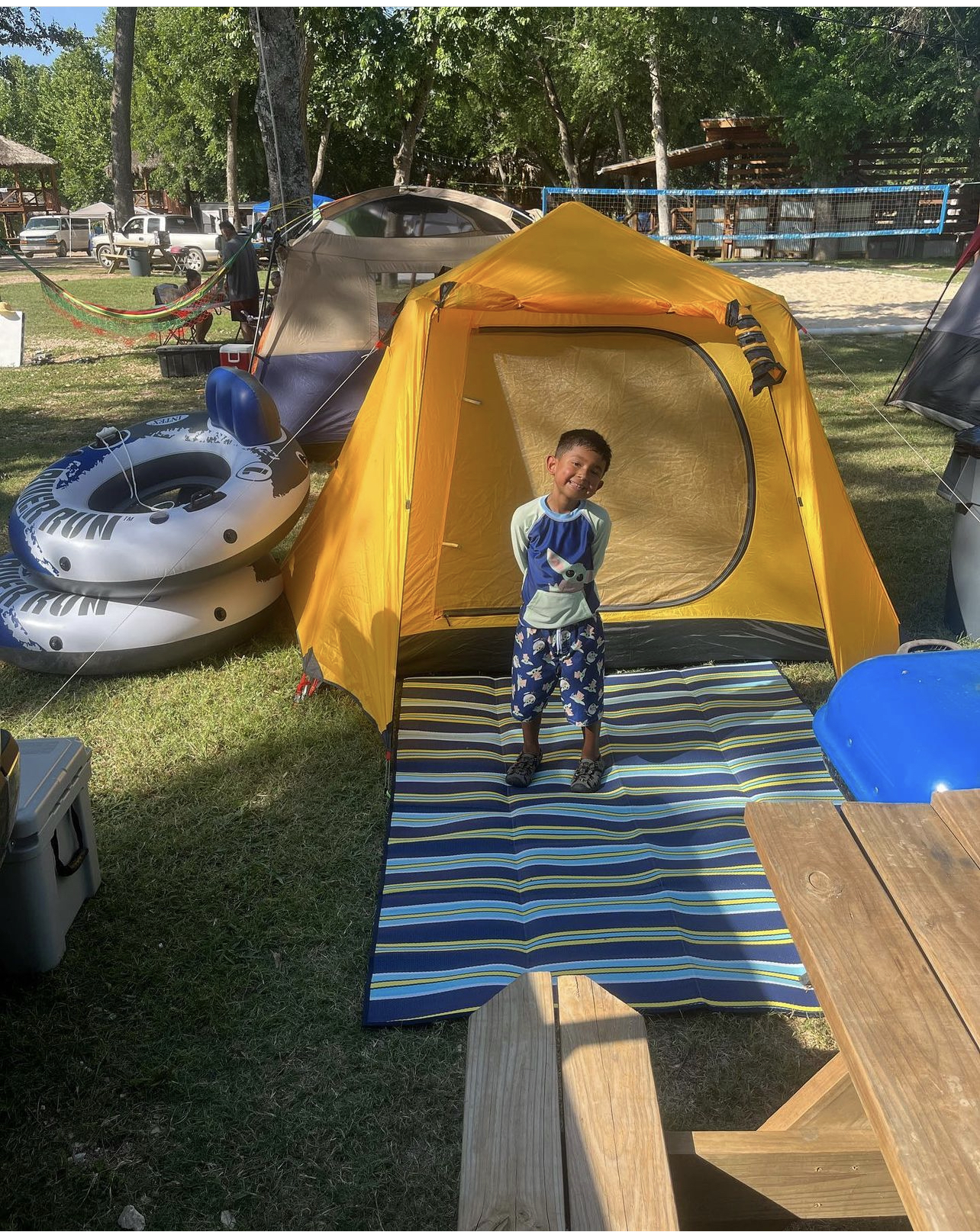 Child at yellow tent with picnic table